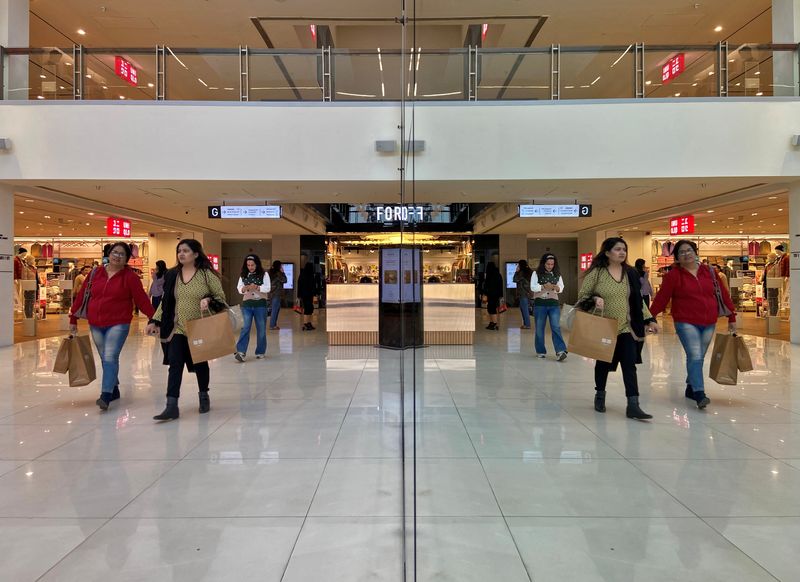 © Reuters. FILE PHOTO: Shoppers are reflected in mirror inside a shopping mall in New Delhi, India, December 14, 2022. REUTERS/Anushree Fadnavis