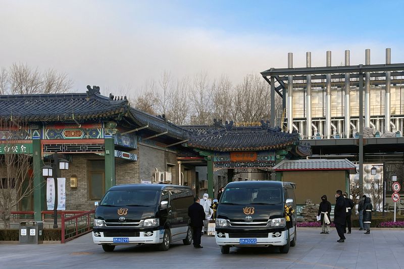 &copy; Reuters. Des travailleurs en combinaison de protection déplacent un cercueil à l'extérieur d'un crématorium dans un salon funéraire, dans le cadre de l'épidémie de coronavirus (COVID-19) à Pékin, en Chine. /Photo prise le 17 décembre 2022/REUTERS/Alessan