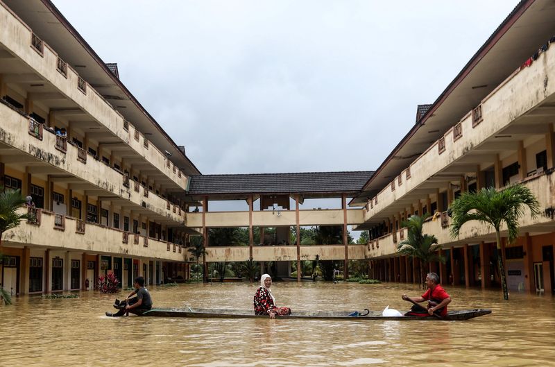 © Reuters. Residents are rescued by a boat from the flood relief centre as the flood water rise and partially submerged the building at Dungun, Terengganu, Malaysia December 21, 2022. More than 70000 were forced into relief centres, with numbers rising in Kelantan, Terengganu and Pahang, according to local media. REUTERS/Stringer