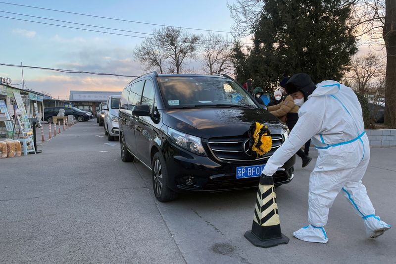 &copy; Reuters. FOTO DE ARCHIVO: Un trabajador con traje protector retira un cono frente a un coche fúnebre en el exterior de una funeraria, en pleno brote de la enfermedad por coronavirus (COVID-19) en Pekín, China, el 17 de diciembre de 2022. REUTERS/Alessandro Divig