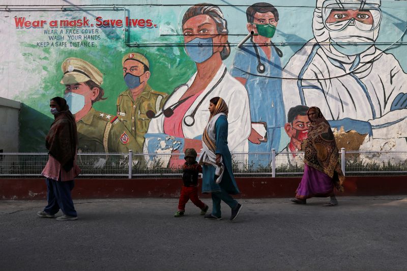 &copy; Reuters. FOTO DE ARCHIVO: Unas mujeres pasan junto a un mural en medio de la pandemia de COVID-19 en Nueva Delhi, India. 7 de febrero, 2022. REUTERS/Anushree Fadnavis/Archivo