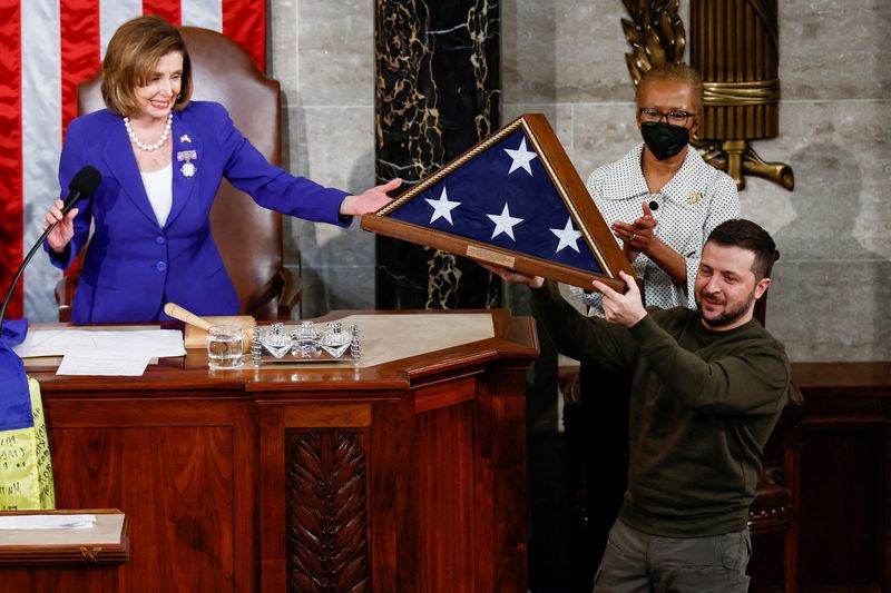 © Reuters. Ukraine's President Volodymyr Zelenskiy receives a U.S. flag from U.S. House Speaker Nancy Pelosi (D-CA) during a joint meeting of the U.S. Congress in the House Chamber of the U.S. Capitol in Washington, U.S., December 21, 2022. REUTERS/Evelyn Hockstein   