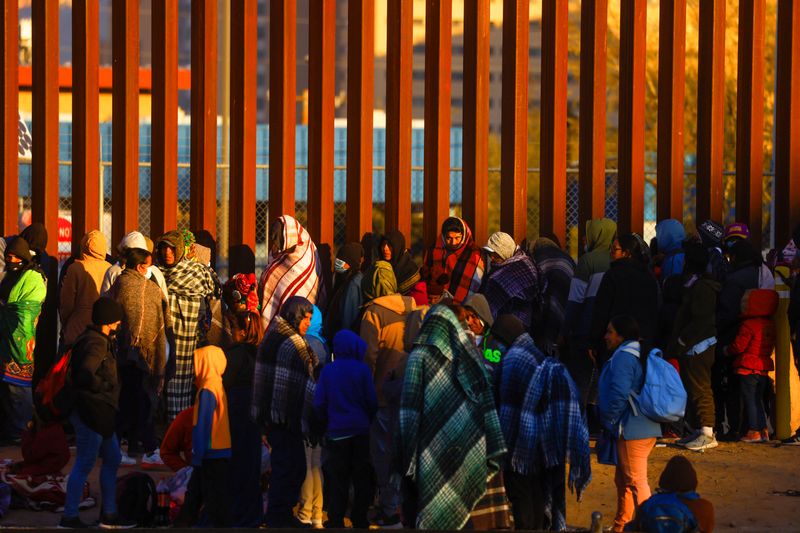 &copy; Reuters. Migrantes hacen fila cerca de la valla fronteriza, después de cruzar el río Bravo, para entregarse a agentes de la Patrulla Fronteriza de Estados Unidos y solicitar asilo, en El Paso, Texas, Estados Unidos, visto desde Ciudad Juárez, México 21 de dici