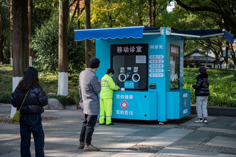 &copy; Reuters. La gente hace cola en una clínica móvil de fiebre que se transformó en una cabina de pruebas de ácido nucleico para la enfermedad por coronavirus (COVID-19), en un parque en Jinhua, provincia de Zhejiang, China 22 de diciembre 2022. Diario de China v