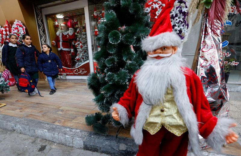 &copy; Reuters. Colegialas palestinas pasan frente a una tienda que vende disfraces de Papá Noel en la ciudad de Gaza, el 22 de diciembre de 2022. REUTERS/Ibraheem Abu Mustafa