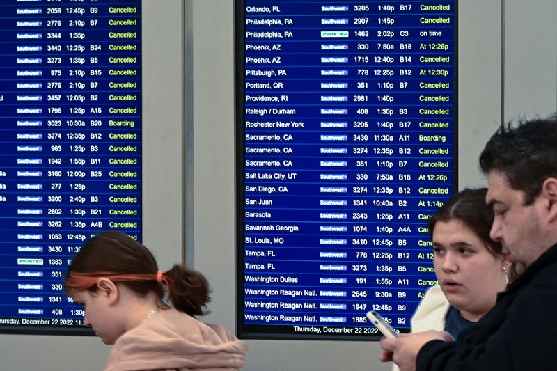 © Reuters. Travelers look over departure notifications as flight cancellations mount as a weather phenomenon known as a bomb cyclone hits the Upper Midwest, at Midway International Airport in Chicago, Illinois, U.S. December 22, 2022.  REUTERS/Matt Marton