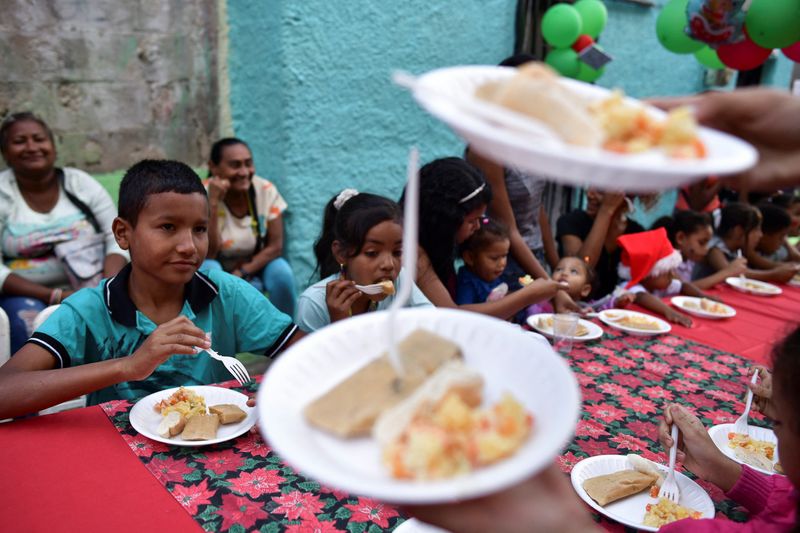 &copy; Reuters. Niños comen "Hallacas", un plato tradicional local, durante una actividad navideña organizada por la ONG "Mi Convive" y la fundación "Gente que necesita amor" en el barrio de "El Cementerio", en Caracas, Venezuela, el 21 de diciembre de 2022. REUTERS/G