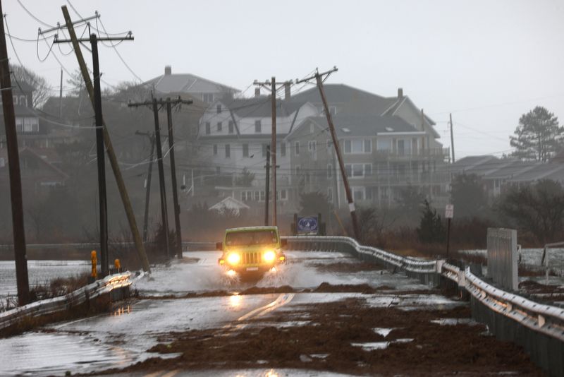 © Reuters. A driver makes their way through a flooded street at high tide during a winter storm in Gloucester, Massachusetts, U.S., December 23, 2022.     REUTERS/Brian Snyder