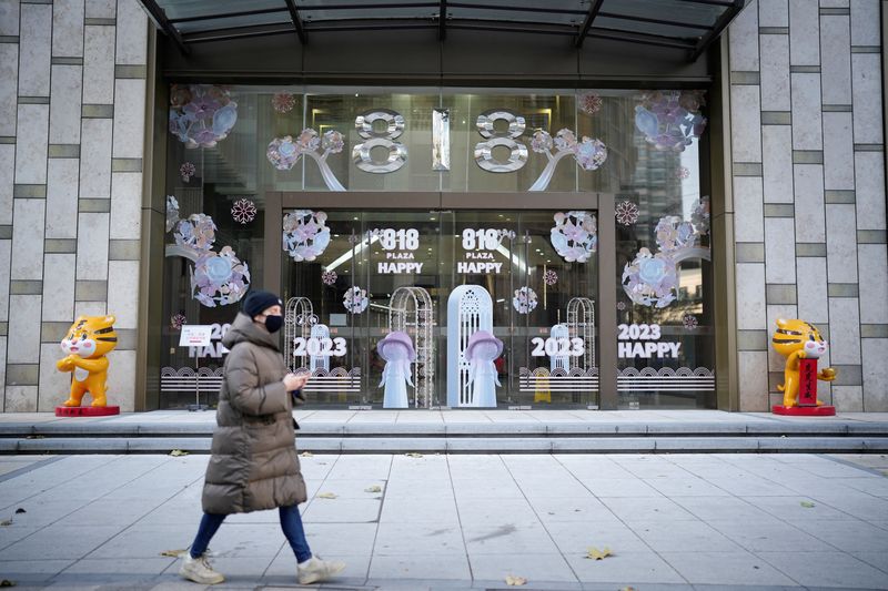 &copy; Reuters. سيدة تضع كمامة تمر بجانب محل تجاري في شنغهاي بالصين يوم 22 ديسمبر كانون الأول 2022. تصوير: آلي سونغ - رويترز.