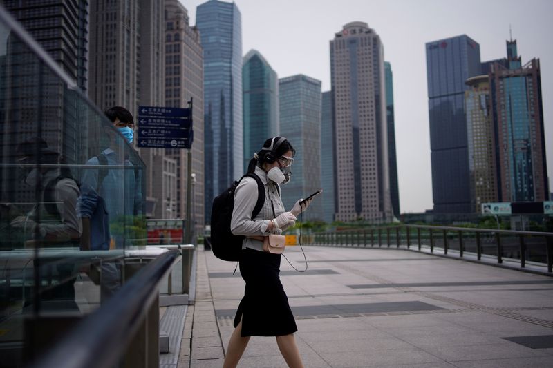 &copy; Reuters. Des personnes portant des masques protecteurs passent devant des immeubles de bureaux dans le quartier financier de Lujiazui à Pudong, à Shangai. /Photo prise le 4 juin 2020/REUTERS/Aly Song
