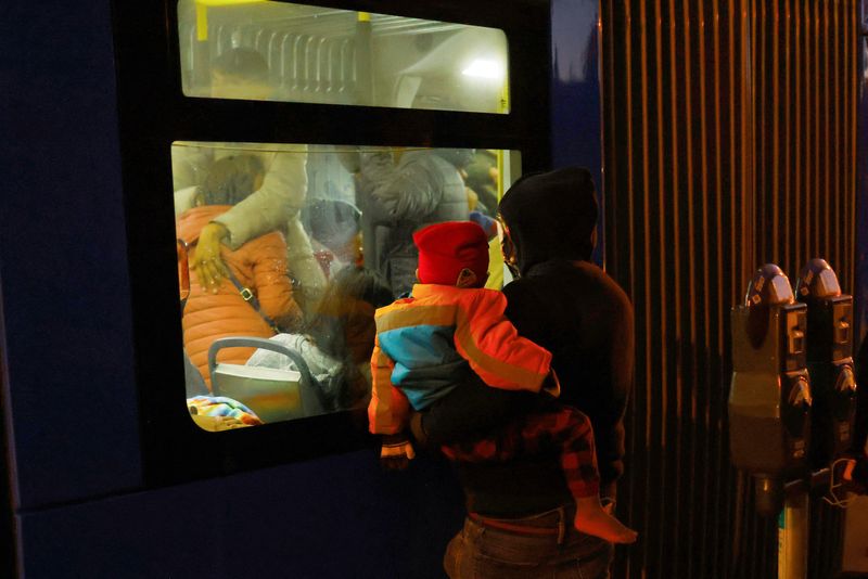 &copy; Reuters. Migrants, mostly from Venezuela, take refuge from the cold on a public transport bus during a night of low temperatures, while another migrant with his son watches them from outside, in downtown El Paso, Texas, U.S., December 23, 2022. REUTERS/Jose Luis G