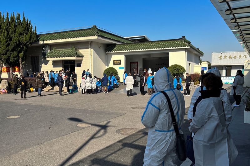 &copy; Reuters. FOTO DE ARCHIVO: Personas con equipos de protección individual (EPI) de pie frente a una funeraria, en medio de un brote de COVID-19 en Shanghái, China. 24 de diciembre, 2022. REUTERS/Personal/Archivo