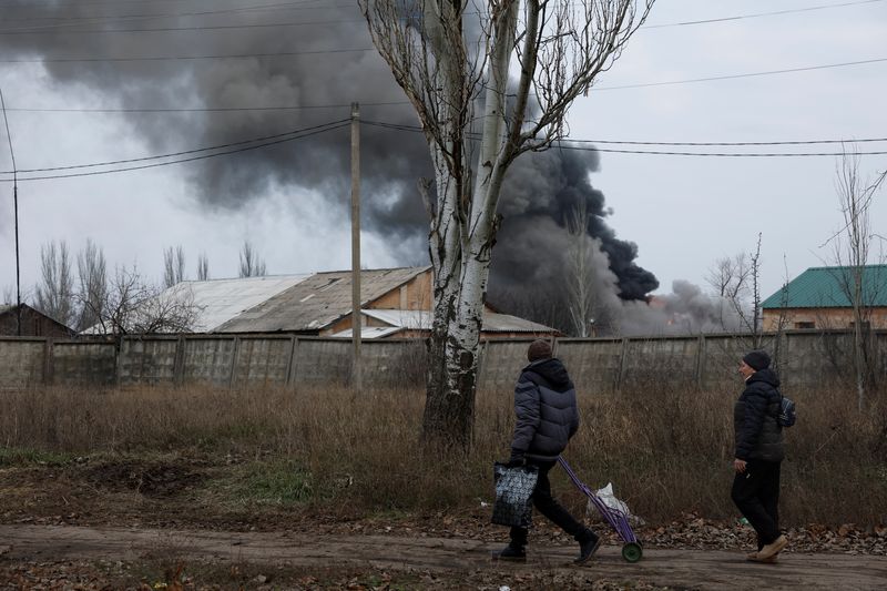 © Reuters. Volodymyr, 61, and Nataliia Bolias, 51, walk past an industrial building that received a missile strike, as Russia's attack on Ukraine continues, during intense shelling on Christmas Day at the frontline in Bakhmut, Ukraine, December 25, 2022. REUTERS/Clodagh Kilcoyne