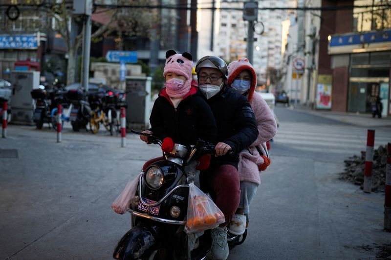 &copy; Reuters. أسرة تضع كمامات واقية بينما يركب أفرادها دراجة نارية داخل أحد شوارع مدينة شنغهاي الصينية في 23 يناير كاون الثاني 2022.  تصوير : على سونج- رويترز .