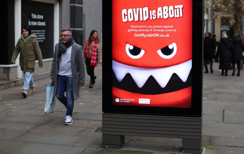 &copy; Reuters. FILE PHOTO: People walk past an advert warning about the coronavirus disease (COVID-19) in Manchester, Britain, November 26, 2022. REUTERS/Phil Noble