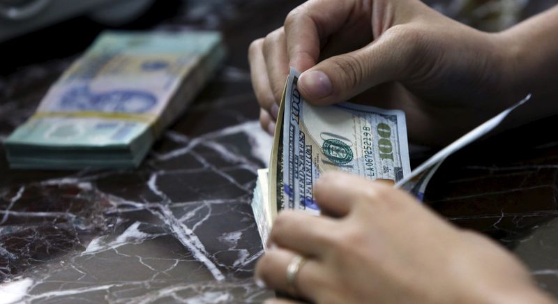 © Reuters. FILE PHOTO: An employee counts U.S. dollar bank-notes near Vietnamese dong bank-notes at a bank in Hanoi, Vietnam August 12, 2015.   REUTERS/Kham