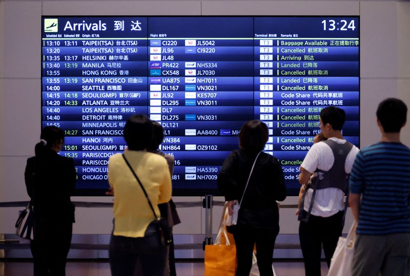 &copy; Reuters. Des personnes devant un panneau d'information sur les vols à l'aéroport international de Haneda, à Tokyo, au Japon. /Photo prise le 11 octobre 2022/REUTERS/Issei Kato