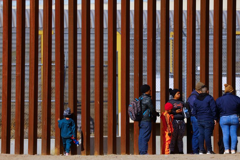 © Reuters. George, 5, a migrant boy from Venezuela traveling with his family, looks through the border wall as they queue to request asylum in El Paso, Texas, United States, seen from Ciudad Juarez, Mexico, December 27, 2022. REUTERS/Jose Luis Gonzalez