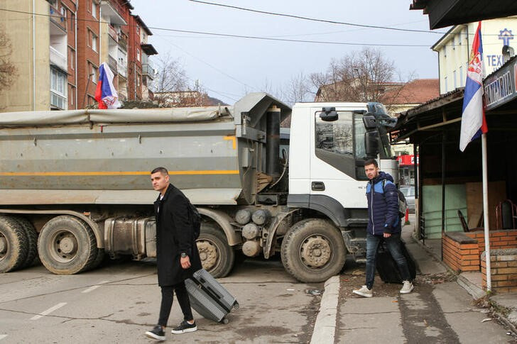 &copy; Reuters. Varias personas cruzan una calle bloqueada por camiones en la parte norte de Mitrovica, Kosovo. 28 diciembre 2022. REUTERS/Miodrag Draskic