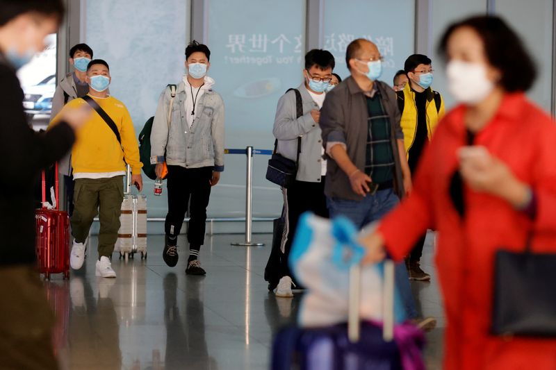 &copy; Reuters. FILE PHOTO: People wearing protective face masks arrive at Capital Airport, following an outbreak of the coronavirus disease (COVID-19), in Beijing, China, November 5, 2020. REUTERS/Thomas Peter