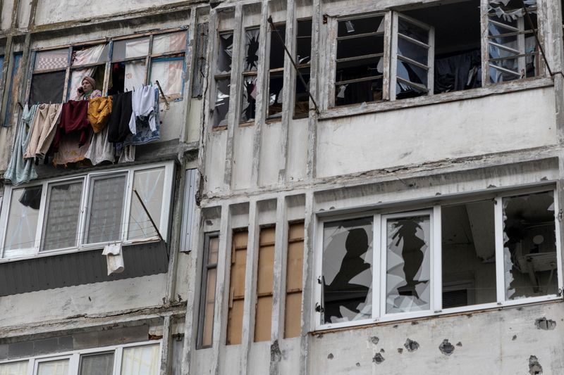 &copy; Reuters. FOTO DE ARCHIVO: Una mujer local habla por su teléfono móvil en una ventana de un edificio residencial dañado por un ataque militar ruso, en medio del ataque de Rusia contra Ucrania continúa, en Jersón, Ucrania, 1 de diciembre de 2022. REUTERS/Anna V