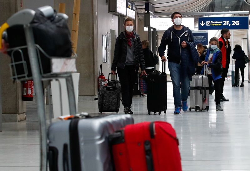 &copy; Reuters. Des personnes portant des masques de protection arrivent à l'aéroport Charles de Gaulle près de Paris, en France. /Photo prise le 29 février 2020/REUTERS/Gonzalo Fuentes