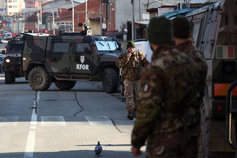 &copy; Reuters. Des membres des forces armées italiennes, qui font partie de la mission de maintien de la paix de l'OTAN au Kosovo, se tiennent près d'un barrage routier dans la partie nord de la ville de Mitrovica, au Kosovo. /Photo prise le 29 décembre 2022/REUTERS/