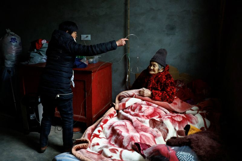 &copy; Reuters. Liao Xiaofeng prepares an oxygen concentrator for her mother Chen Lifen as they arrive home from a clinic in a village of Lezhi county after strict measures to curb the coronavirus disease (COVID-19) were removed nationwide, in Ziyang, Sichuan province, C