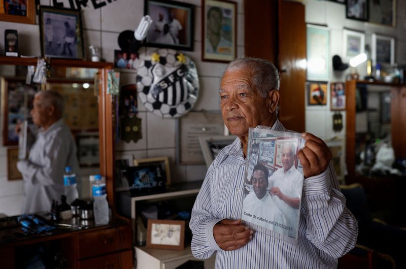 © Reuters. Joao Araujo, know as Didi, 84, who was hairdresser to Brazilian soccer legend Pele, holds a picture of himself with Pele, as he mourns his death, in Santos, Brazil, December 30, 2022. REUTERS/Amanda Perobelli