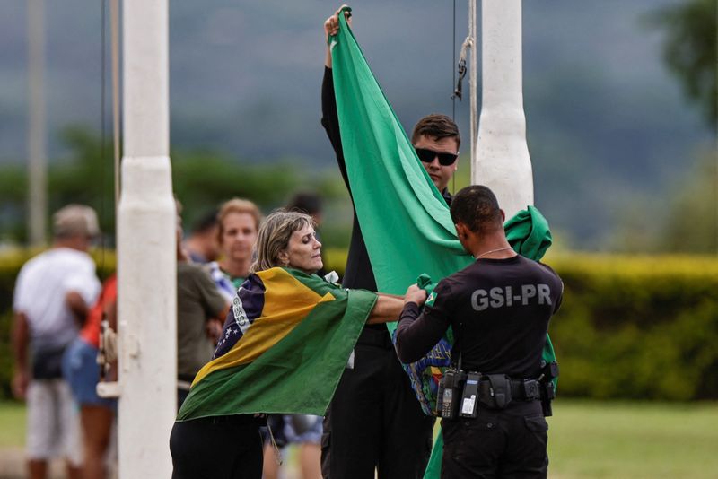 &copy; Reuters. Deise Casela toca a bandeira presidencial brasileira enquanto é retirada por agentes do GSI em frente ao Palácio da Alvorada, em Brasília
30/12/2022
REUTERS/Ueslei Marcelino