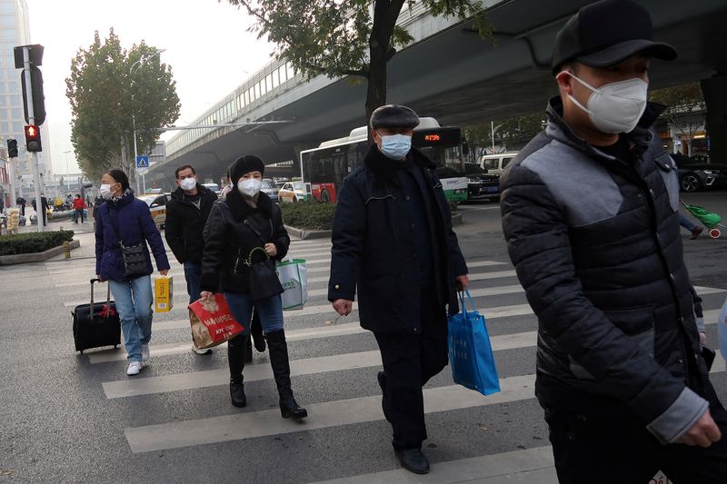 &copy; Reuters. أشخاص يسيرون في أحد شوارع مدينة ووهان الصينية يوم السبت. تصوير: تينجشو وانج – رويترز.
