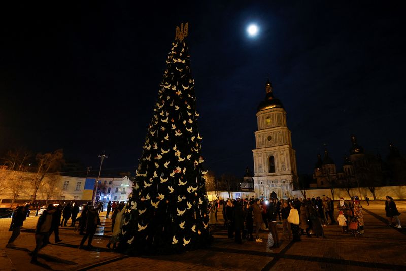 &copy; Reuters. Des personnes se sont rassemblées près d'un arbre de Noël pour célébrer la veille du Nouvel An avant un couvre-feu devant la cathédrale Sainte-Sophie à Kyiv, en Ukraine. /Photo prise le 31 décembre 2022/REUTERS/Valentyn Ogirenko