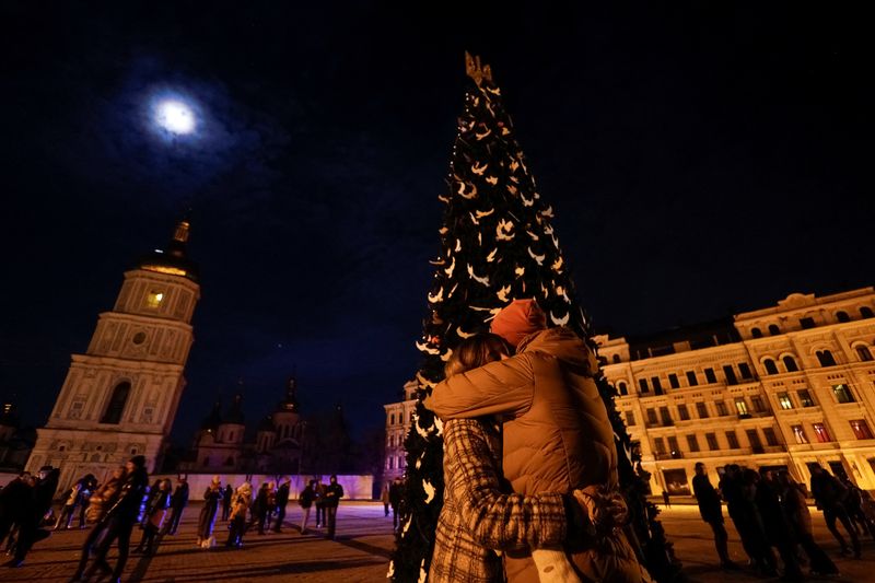 &copy; Reuters. Un couple s'embrasse près d'un arbre de Noël lors d'une célébration de la veille du Nouvel An devant la cathédrale Sainte-Sophie à Kyiv, en Ukraine. /Photo prise le 31 décembre 2022/REUTERS/Valentyn Ogirenko