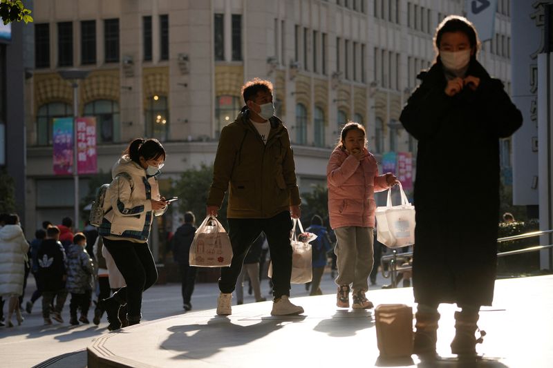 &copy; Reuters. أشخاص يضعون كمامات يسيرون في منطقة تسوق في شنغهاي بالصين يوم الثلاثاء. تصوير: آلي سونغ - رويترز.