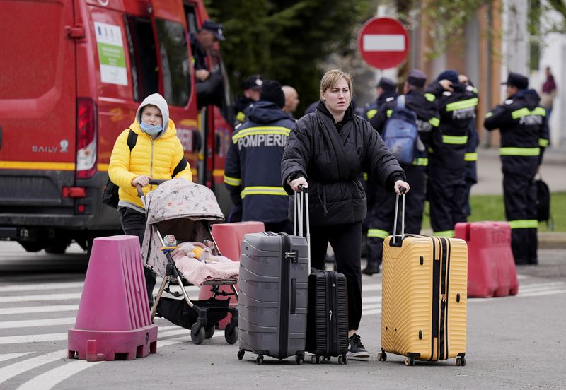 &copy; Reuters. FILE PHOTO: A woman walks with her luggage as a young adult pushes a baby in a stroller after fleeing from Ukraine to Romania, amid the Russian invasion of Ukraine, at the border crossing point in Siret, Romania April 16, 2022. REUTERS/Fedja Grulovic