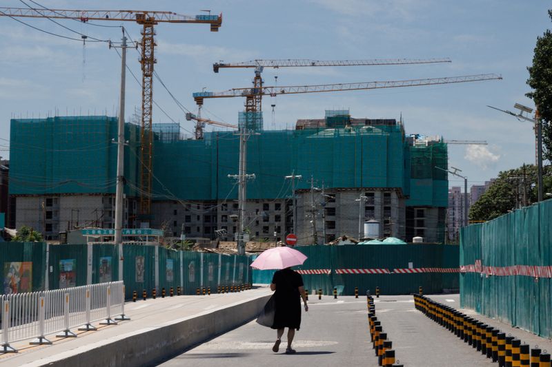 © Reuters. FILE PHOTO: A woman walks near a construction site of apartment buildings in Beijing, China, July 15, 2022. REUTERS/Thomas Peter