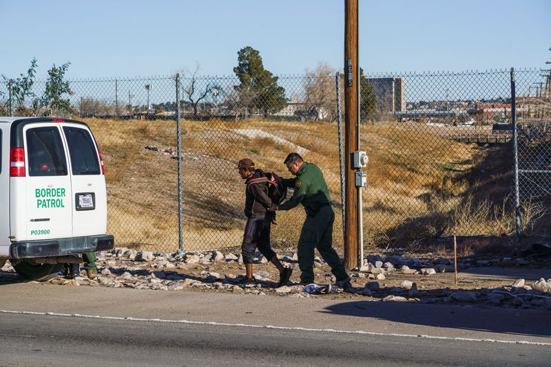 © Reuters. A migrant man is escorted by a United States Border Patrol agent after being apprehended crossing the U.S.-Mexico border along Texas 375 Loop in El Paso, Texas, U.S., January 4, 2023.  REUTERS/Paul Ratje
