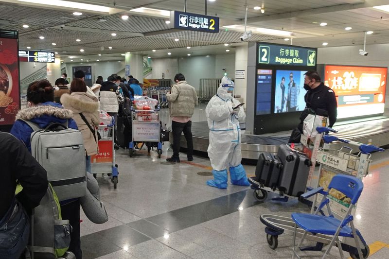 &copy; Reuters. Passengers arriving on international flights wait in line next to a staff member wearing personal protective equipment (PPE) at the airport in Chengdu, China January 6, 2023. REUTERS/Staff