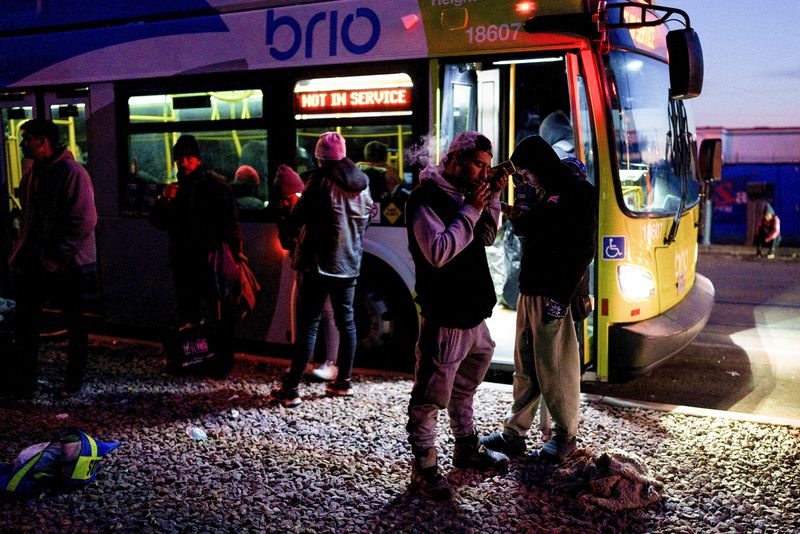 &copy; Reuters. Migrantes, en su mayoría de Venezuela, de pie junto a un autobús usado para mantener a la gente caliente junto a la Iglesia del Sagrado Corazón en el centro de El Paso, Texas, Estados Unidos. 5 de enero de 2023. REUTERS/Paul Ratje 