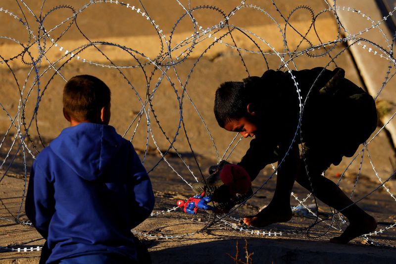 &copy; Reuters. Santiago, um menino migrante de 8 anos da Colômbia que está viajando com sua família e buscando asilo nos Estados Unidos, carrega um boneco do Homem-Aranha enquanto tenta atravessar um arame farpado que foi colocado pela Guarda Nacional do Texas no fro