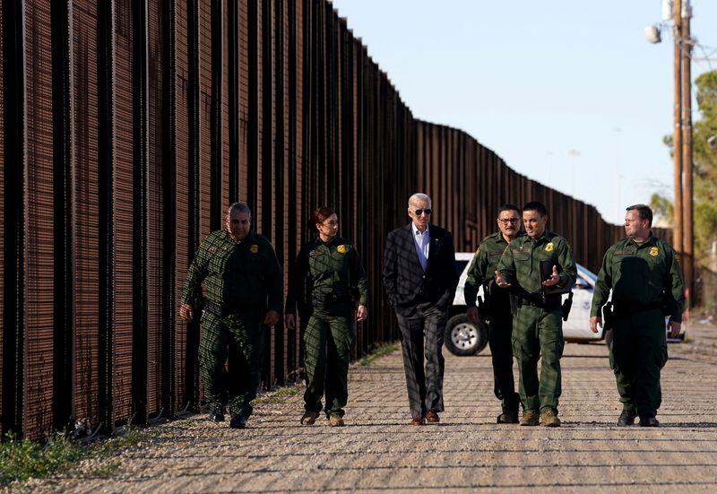 &copy; Reuters. 　バイデン米大統領（写真左から３人目）は８日、大統領就任後初めてメキシコとの国境を訪れ、両国を隔てる壁や陸橋を視察した。写真は国境のフェンス沿いを歩きながら国境警備隊員と