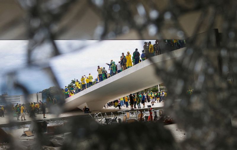 © Reuters. Supporters of Brazil's former President Jair Bolsonaro are pictured through broken glass as they hold a demonstration against President Luiz Inacio Lula da Silva, in Brasilia, Brazil, January 8, 2023. REUTERS/Adriano Machado 