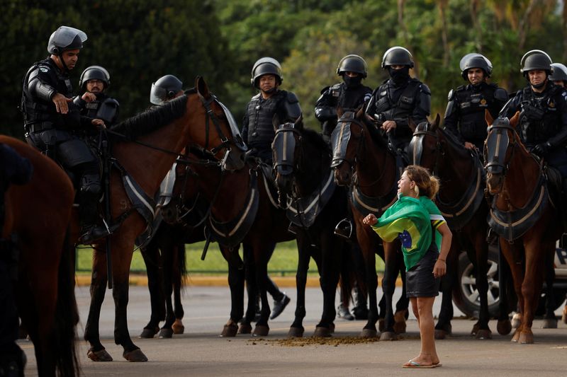 © Reuters. Un manifestante reacciona junto a miembros de las fuerzas de seguridad mientras partidarios del expresidente de Brasil Jair Bolsonaro abandonan un campamento frente al Cuartel General del Ejército, en Brasilia, Brasil, 9 de enero de 2023. REUTERS/Amanda Perobelli