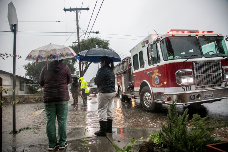 © Reuters. Residents stand near a fire truck on a flooded street in east Santa Barbara, California, U.S. January 9, 2023.  REUTERS/Erica Urech