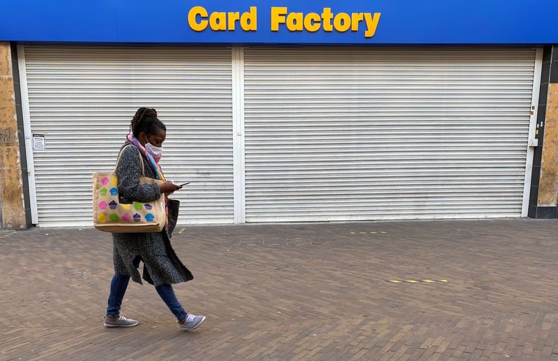 &copy; Reuters. A woman wearing a face mask looks at a smartphone as she walks past a shuttered branch of Card Factory in Hackney, following the outbreak of the coronavirus disease (COVID-19), London, Britain, June 2, 2020. REUTERS/Simon Newman/Files