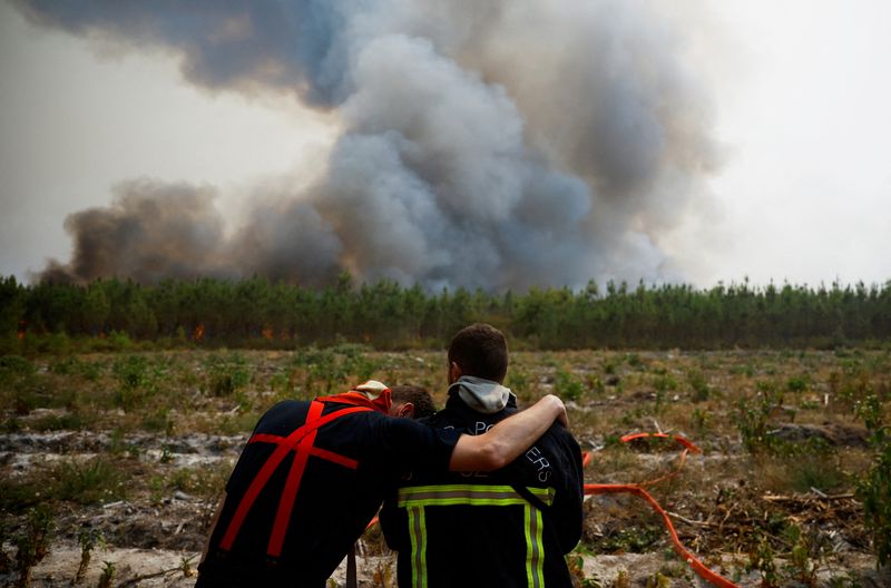 © Reuters. FILE PHOTO: Firefighters embrace as they work to contain a fire in Saint-Magne, as wildfires continue to spread in the Gironde region of southwestern France, August 11, 2022. REUTERS/Stephane Mahe  