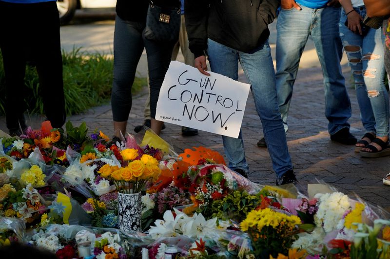 © Reuters. FILE PHOTO: A mourner holds a sign advocating for gun control while visiting a memorial for victims of a mass shooting at a Fourth of July parade in the Chicago suburb of Highland Park, Illinois, U.S. July 7, 2022. REUTERS/Cheney Orr/File Photo