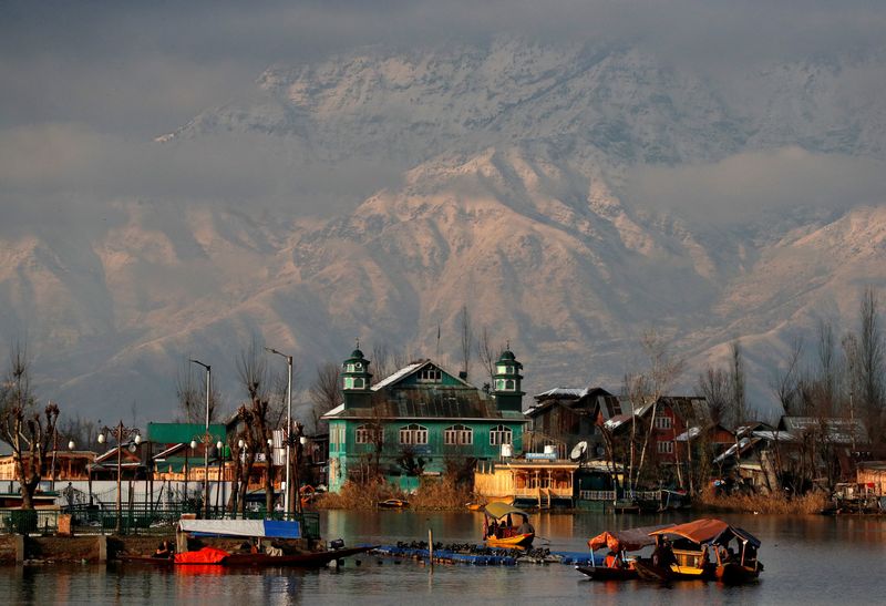 © Reuters. FILE PHOTO: People row their boats in the waters of Dal Lake with the backdrop of snow-covered mountains after a snowfall in Srinagar December 12, 2020. REUTERS/Danish Ismail/File Photo