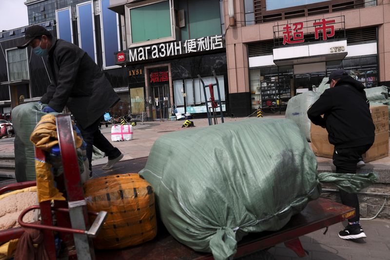 &copy; Reuters. Men move bags of goods for export in front of a trading centre that houses shops and offices with Russian goods and services, in Beijing, China April, 1 2022. REUTERS/Tingshu Wang