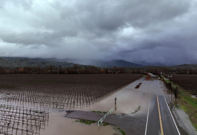 © Reuters. Dark storm clouds are seen above farmland and Highway 175 which were covered with floodwater in Hopland, California, U.S. January 14, 2023.  REUTERS/Fred Greaves